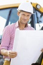 Portrait of male architect holding blueprint at construction site