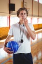 Portrait of male basketball coach with whistle and ball