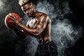 Portrait of afro-american sportsman, basketball player with a ball over black background. Fit young man in sportswear Royalty Free Stock Photo