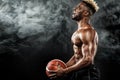 Portrait of afro-american sportsman, basketball player with a ball over black background. Fit young man in sportswear Royalty Free Stock Photo