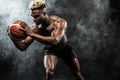 Portrait of afro-american sportsman, basketball player with a ball over black background. Fit young man in sportswear Royalty Free Stock Photo