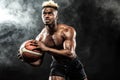 Portrait of afro-american sportsman, basketball player with a ball over black background. Fit young man in sportswear Royalty Free Stock Photo