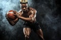 Portrait of afro-american sportsman, basketball player with a ball over black background. Fit young man in sportswear Royalty Free Stock Photo