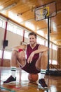 Portrait of male basketball player sitting on ball Royalty Free Stock Photo
