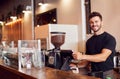 Portrait Of Male Coffee Shop Owner Standing At Sales Desk