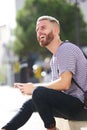 Male college student smiling outside with mobile phone Royalty Free Stock Photo