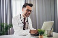 Male, doctor sitting in medical office using digital tablet Royalty Free Stock Photo