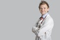 Portrait of a male doctor smiling with arms crossed over gray background Royalty Free Stock Photo