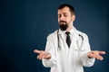 Male doctor with stethoscope in medical uniform showing showing red and blue pills on hands, in doubt Royalty Free Stock Photo