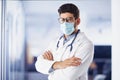 Male doctor portrait while wearing face mask and standing at hospital`s foyer Royalty Free Stock Photo