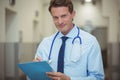 Portrait of male doctor writing on clipboard in corridor Royalty Free Stock Photo