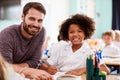 Portrait Of Male Elementary School Teacher Giving Female Pupil Wearing Uniform One To One Support Royalty Free Stock Photo