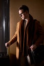 Side view portrait of man in eyeglasses standing with luggage, waiting for someone in hotel hall Royalty Free Stock Photo