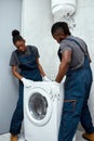 Young African American couple of technicians setting up washing machine Royalty Free Stock Photo