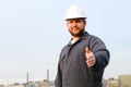 Portrait of male foreman with outstetched hands standing in construction site background. Royalty Free Stock Photo