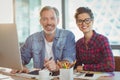 Portrait of male graphic designer sitting with coworker in office Royalty Free Stock Photo