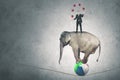 Male manager juggling balls above an elephant