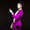 Portrait of male mime artist, isolated on black background. Man in a purple suit is standing with risen finger. Symbol