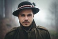 Portrait of male model with hat and beautiful eyes in deep forest at twilight. Woodsman in misty and foggy forest looking to the