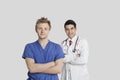 Portrait of male nurse and doctor standing with arms crossed over gray background Royalty Free Stock Photo