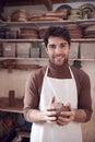 Portrait Of Male Potter Wearing Apron Holding Lump Of Clay In Ceramics Studio