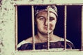 Portrait of male prisoner standing behind a prison grid in a jail cell Royalty Free Stock Photo