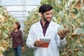 Portrait of a male researcher examining the quality of a melon plantation in a large greenhouse