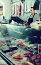 Portrait of male seller posing with wursts in butchery