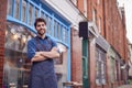 Portrait Of Male Small Business Owner Wearing Apron Standing Outside Shop On Local High Street