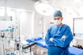 Portrait of male surgeon in operating room with surgery lights on and medical devices. Modern hospital details