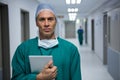 Portrait of male surgeon standing with digital tablet in corridor