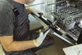 Male Technician Repairing Dishwasher In Kitchen Royalty Free Stock Photo