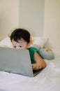 A male toddler is playing with a laptop while on the bed Royalty Free Stock Photo