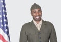 Portrait of a male US soldier smiling with American flag over gray background