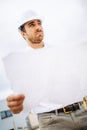 portrait of male worker on construction site, wearing hard hat and reading blueprints Royalty Free Stock Photo