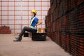 Portrait of a male worker wearing a safety vest and helmet sitting on a steels pallet due to back pain Royalty Free Stock Photo