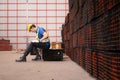 Portrait of a male worker wearing a safety vest and helmet sitting on a steels pallet due to back pain Royalty Free Stock Photo