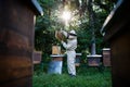 Portrait of man beekeeper working in apiary, using bee smoker. Royalty Free Stock Photo