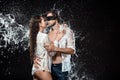 portrait of man with black ribbon on eyes hugging sexy girlfriend near by while swilled with water