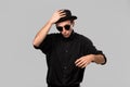 Portrait of a man in a black shirt, pork pie and sun glasses hat isolated over grey background. Royalty Free Stock Photo