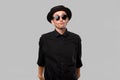 Portrait of a man in a black shirt, pork pie and sun glasses hat isolated over grey background. Royalty Free Stock Photo