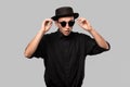 Portrait of a man in a black shirt, pork pie and sun glasses hat isolated over grey background. Royalty Free Stock Photo