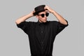 Portrait of a man in a black shirt, pork pie and sun glasses hat isolated over grey background. Royalty Free Stock Photo