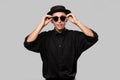 Portrait of a man in a black shirt, pork pie and sun glasses hat isolated over grey background. Royalty Free Stock Photo