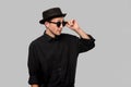 Portrait of a man in a black shirt, pork pie and sun glasses hat  over grey background. Royalty Free Stock Photo