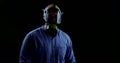 Portrait of a man in a blue shirt and white protective gloves on a black background. he adjusts the respirator straps