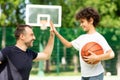 Portrait of man and boy giving high five playing basketball Royalty Free Stock Photo