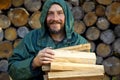 Portrait of a man with a bunch of chopped firewood. Bearded lumberjack with firewood for the fireplace.