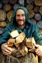 Portrait of a man with a bunch of chopped firewood. Bearded lumberjack with firewood for the fireplace. Royalty Free Stock Photo