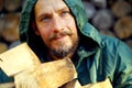 Portrait of a man with a bunch of chopped firewood. Bearded lumberjack with firewood for the fireplace. Royalty Free Stock Photo